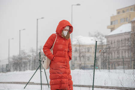 Prague, Czech Republic. 02-23-2021. Woman with mask is walking in the city center of Prague on a cold winter snow day.のeditorial素材