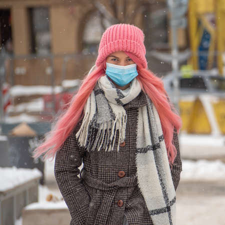 Prague, Czech Republic. 02-23-2021. Young trendy woman with pink hair with mask is walking in the city center of Prague on a cold winter day.のeditorial素材
