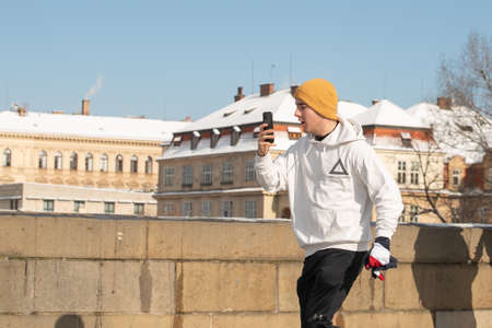 Prague, Czech Republic. 02-23-2021. Young sportive man running with phone in the city center of Prague on the Charles Bridge, enjoying a cold day during winterのeditorial素材
