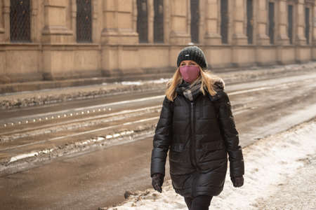 Prague, Czech Republic. 02-23-2021. Young woman with mask is walking in the city center of Prague on a cold winter day.のeditorial素材