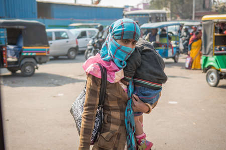 Jaipur, India. 09-05-2018. Mother carrying her son while walking at the local fruits and vegetables in the market of Jaipur.のeditorial素材