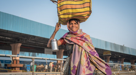 Jaipur, India. 09-05-2018. Smiling woman is walking with her belongings on her head at the main...