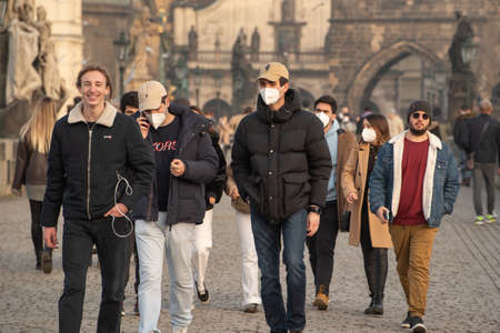 Prague, Czech Republic. 03-02-2021. Young males with mask walking on the Charles Bridge in the city...