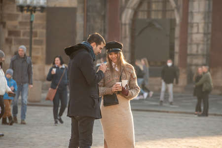 Prague, Czech Republic. 03-02-2021. A romantic young couple are talking, smiling and having fun in the Old Square in the city center of Prague on a beautiful sunset during winter.のeditorial素材