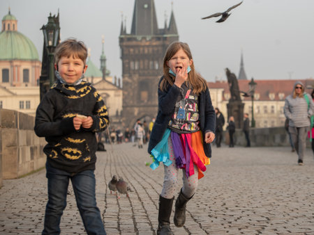 Prague, Czech Republic. 03-02-2021. Two kids walking and having good fun on the Charles Bridge in the city center of Prague during winter with a beautiful sunset.のeditorial素材