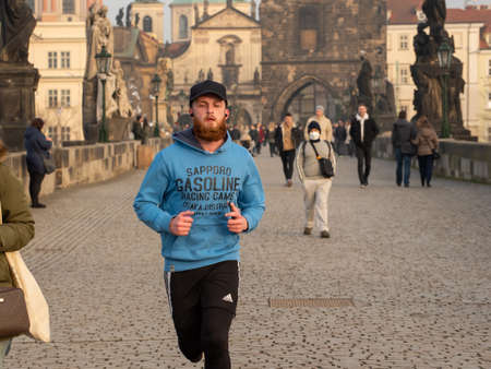 Prague, Czech Republic. 03-02-2021. Young male running on the Charles Bridge in the city center of Prague during winter with a beautiful sunset.のeditorial素材