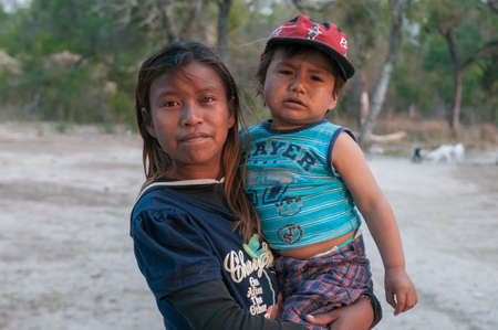 Chaco. Argentine. 15-01-2019. Indigenous girl carrying her small brother by the arms in Chaco Province, in the North of Argentine.のeditorial素材