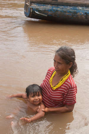 Darien Province, Panama. 07-18-2019. An indigenous grandmother is holding his grand son in the water.のeditorial素材