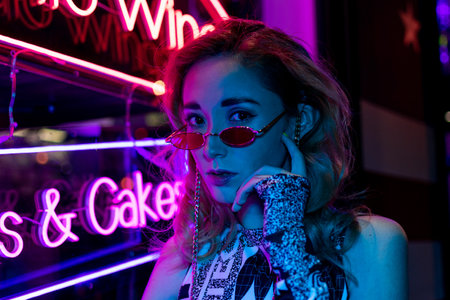 Lovely young millennials woman with glasses on the street with neon backgroundの写真素材