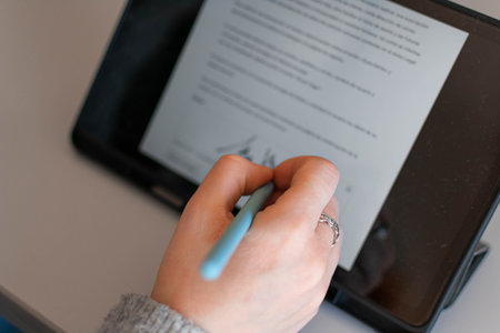 Close-up image of a female hand holding a pen and writing in a notebookの写真素材