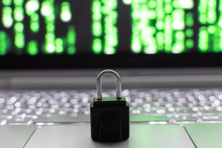 Padlock on laptop keyboard in front of green defocused background.の写真素材