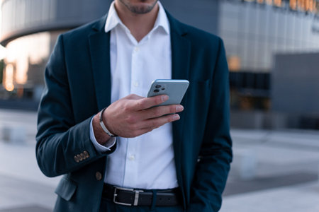cropped view of businessman in formal wear using smartphone on city streetの写真素材