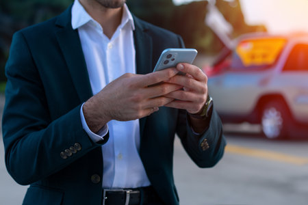 Cropped image of young businessman in suit using mobile phone outdoors.の写真素材