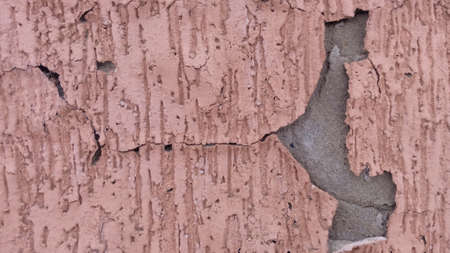 Texture of pink plaster in cracks old cover rough surface cracked wall
