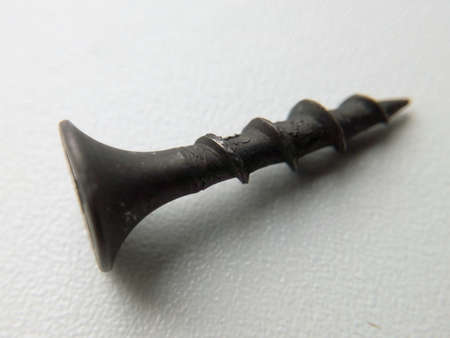 Screw of a self-tapping black close-up on a white porous background with a blurred backgroundの写真素材