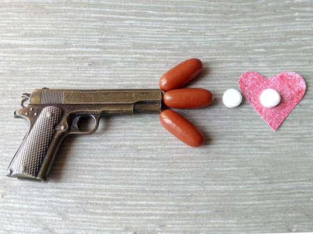 Shot pills in a red heart sign, depending on drugs or medications suicide gun pills medicationの写真素材