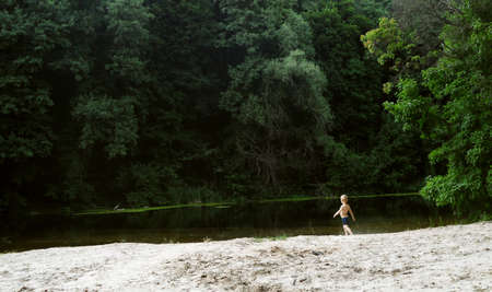 Boy on the background of the river in summer sunny afternoonの写真素材
