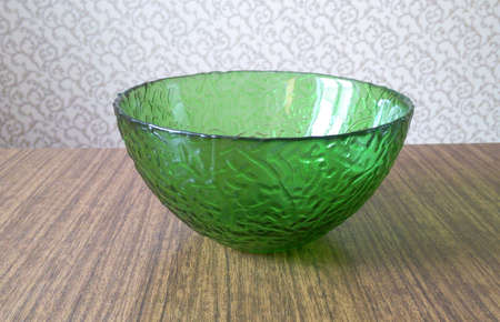 Green glass plate on a brown table on a background of wallpaper blurred backgroundの写真素材