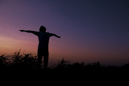 A man  stretching the arms and turning the face upwards, silhouette の写真素材