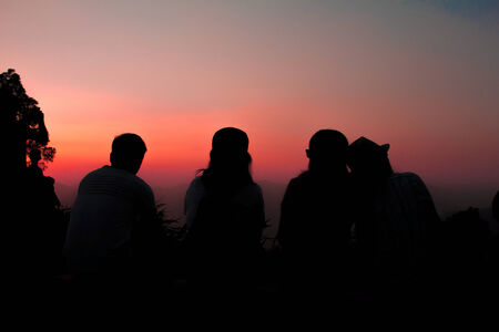 Friends sitting together watching sunset, silhouetteの写真素材