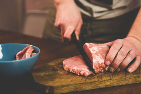 I cut pork with a knife on a wooden boardの写真素材
