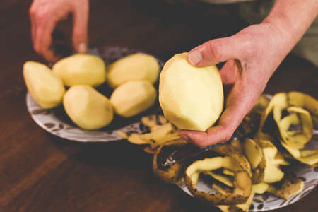 Peeling potatoes with a knife at homeの写真素材