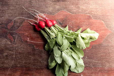 Red radish on a wooden table. Red vegetable with green leaves.の写真素材