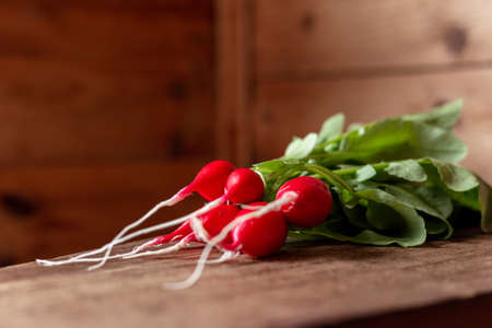 Red radish on a wooden table. Red vegetable with green leaves.の写真素材