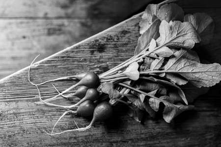 Red radish on a wooden table. Red vegetable with green leaves.の写真素材