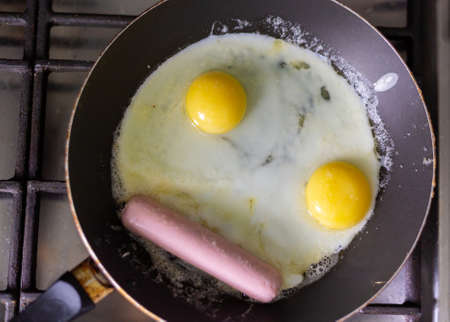 Fried eggs with sausage in a panの写真素材
