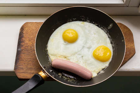 Fried eggs with sausage in a panの写真素材