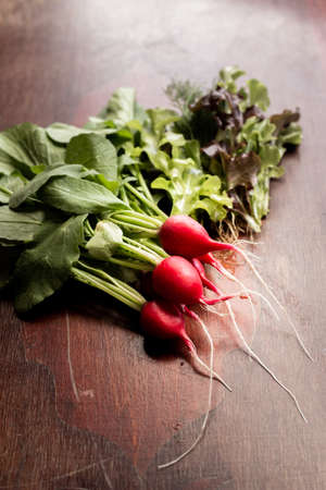 Red radish on a wooden table. Red vegetable with green leaves.の写真素材