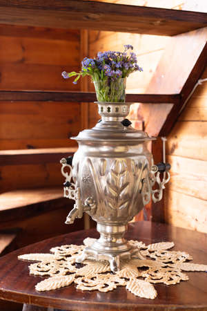 Old metal samovar and a bouquet of blue flowers on a wooden backgroundの写真素材