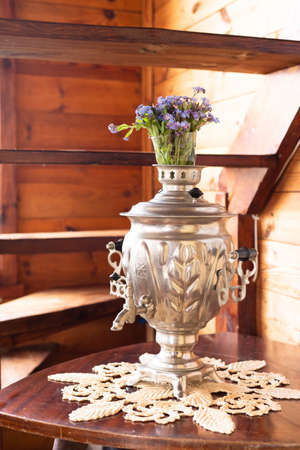 Old metal samovar and a bouquet of blue flowers on a wooden backgroundの写真素材