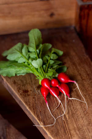 Red radish on a wooden table. Red vegetable with green leaves.の写真素材