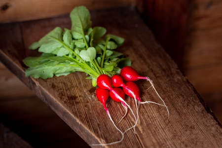 Red radish on a wooden table. Red vegetable with green leaves.の写真素材