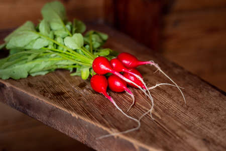 Red radish on a wooden table. Red vegetable with green leaves.の写真素材