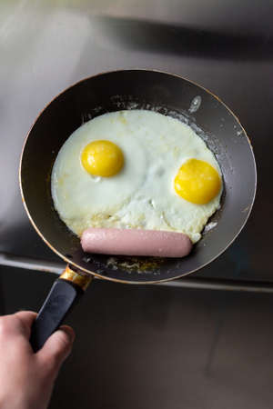 Fried eggs with sausage in a panの写真素材