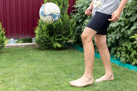 Footballer barefoot stuffs the ball on the green grass.の写真素材