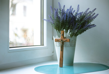 Wooden cross and lavender bouquet by the windowの写真素材