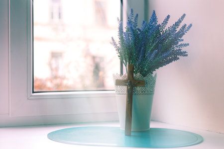 Wooden cross and lavender bouquet by the windowの写真素材