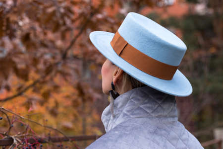 Woman in a blue hat standing with her back.