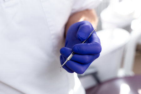 Male hands in blue medical gloves hold a dental instrumentの写真素材
