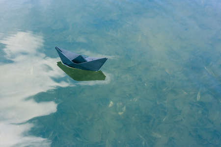 Black paper boat floats on the river