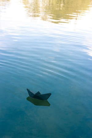 Black paper boat floats on the riverの写真素材
