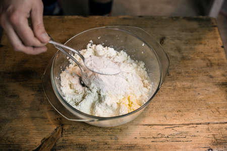 Knead the cottage cheese with eggs in a bowl with a spoonの写真素材