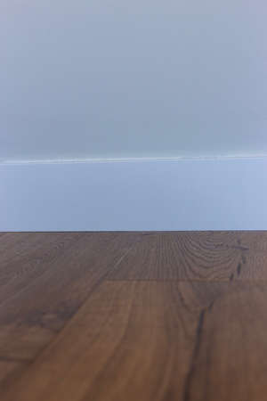 White baseboard, white wall and wood laminate.の写真素材