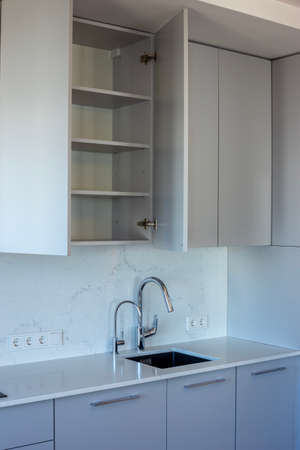Kitchen with open cabinet and empty shelvesの写真素材