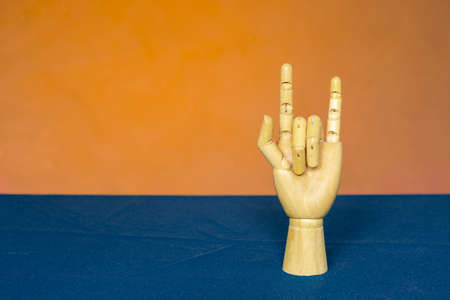 Wooden hand with two fingers on a yellow-blue backgroundの写真素材
