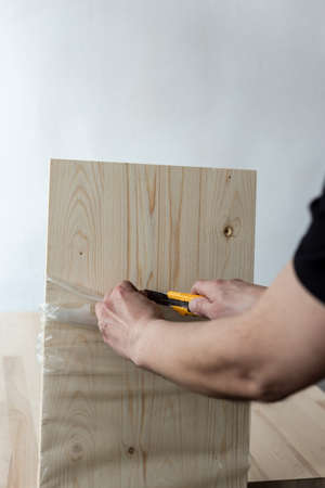 Unpacking a furniture board with a knife. Unpacking a wooden board.の写真素材